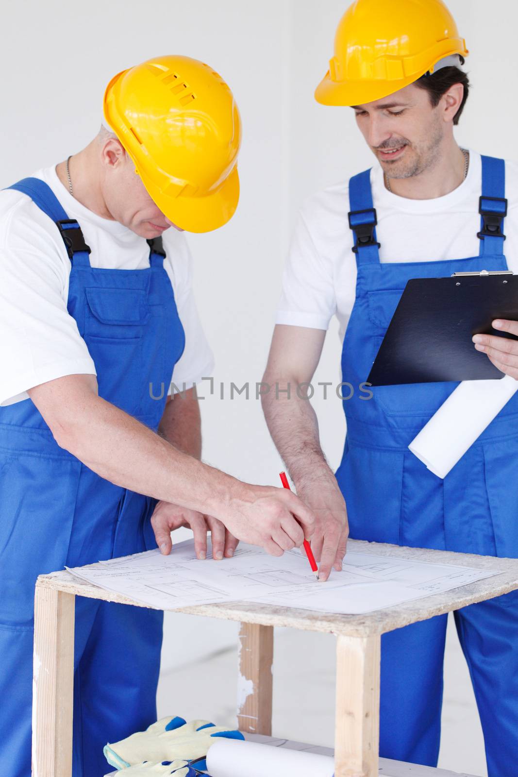 Two workers correcting a construction plan