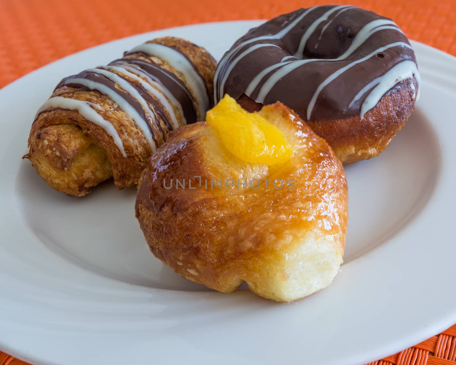 In the pictured three pastries served on a white plate .