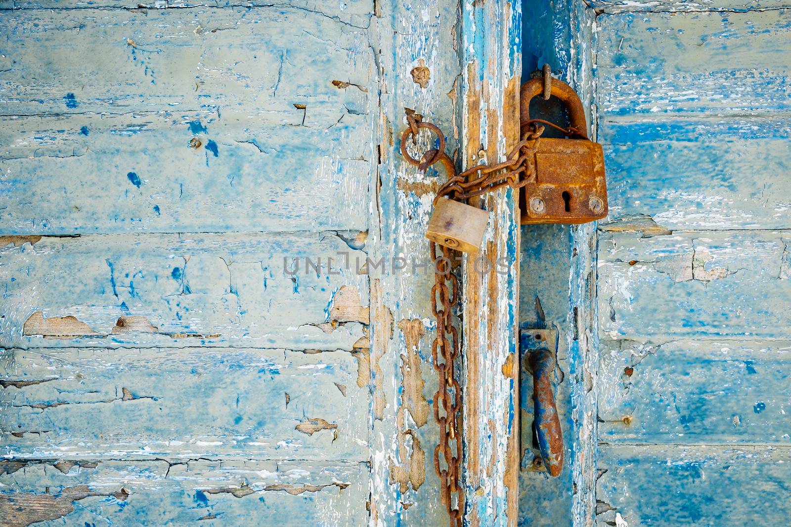 Old rusty padlock and chain on weathered textured door