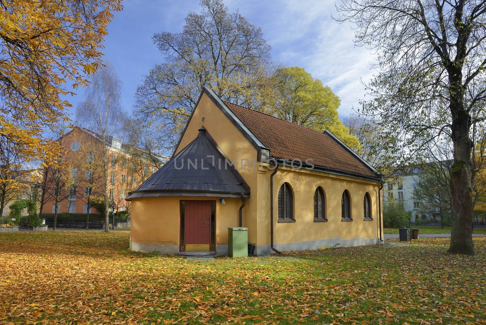 Beautiful fall Chapel in Stockholm (Sweden). Leafs are turning red and have fallen all around it.