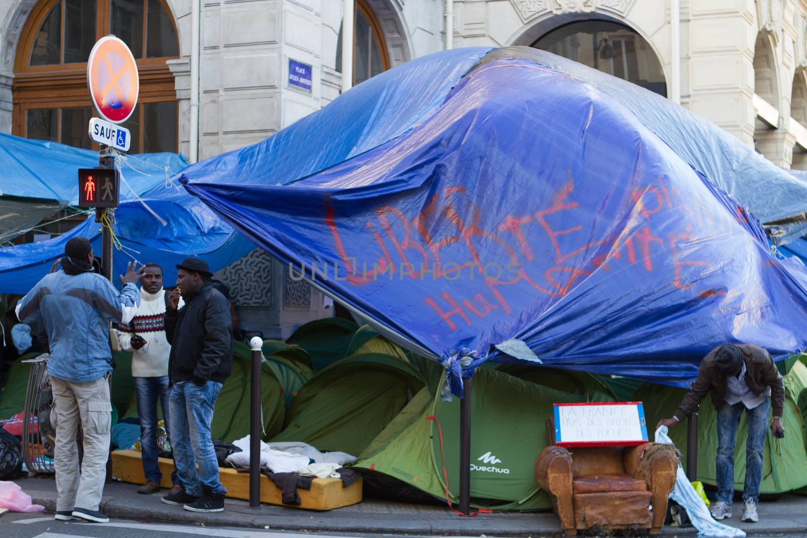 FRANCE, Paris: Three refugees have a conversation in their camp in front of the city hall of the 18th arrondissement in Paris, on September, 15, 2015. Almost hundred and fifty refugees from South Soudan and Eritrea camp in front of the city hall of the 18th arrondissement in Paris since September, 4, 2015. Paris mayor Anne Hidalgo announced on September, 15, 2015 giving them a place in one of the seven installations opened in the capital and around las week. 