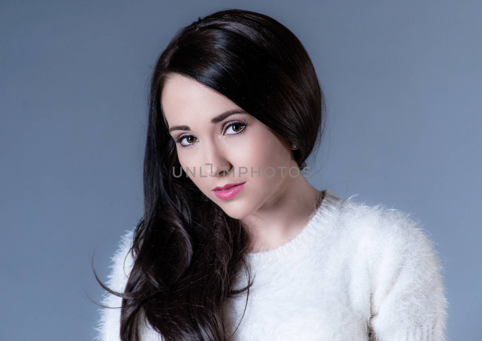 beautiful dark haired woman in white sweater on blue background