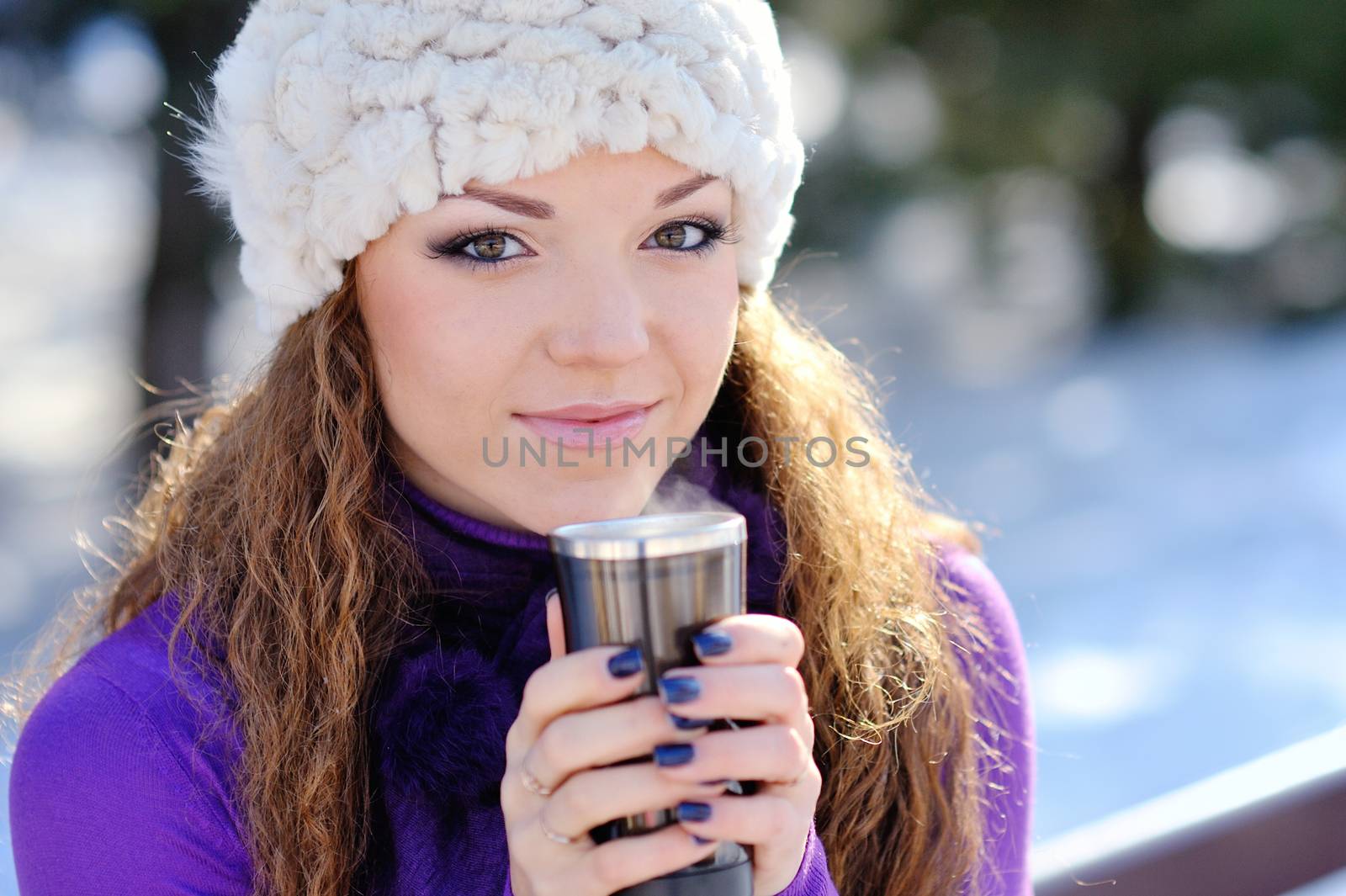 Young beautiful girl sitting on the bench with cup of coffee at winter
