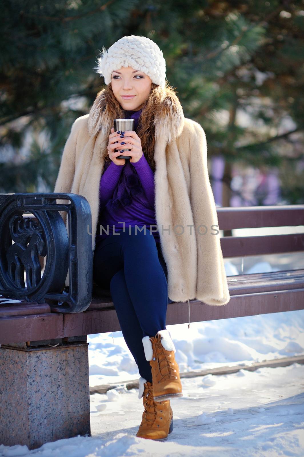 Portrait beautiful girl sitting on the bench in winter forest