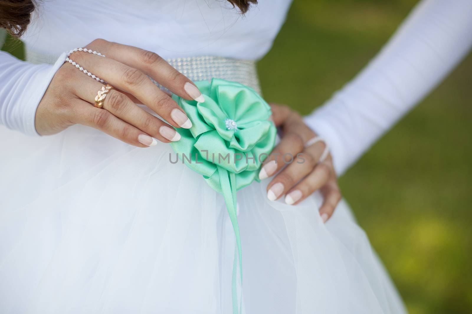 bride adjusts flower on her dress by timonko