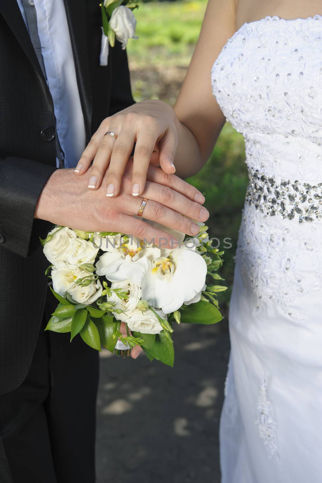 hand the bride and groom with rings on wedding bouquet