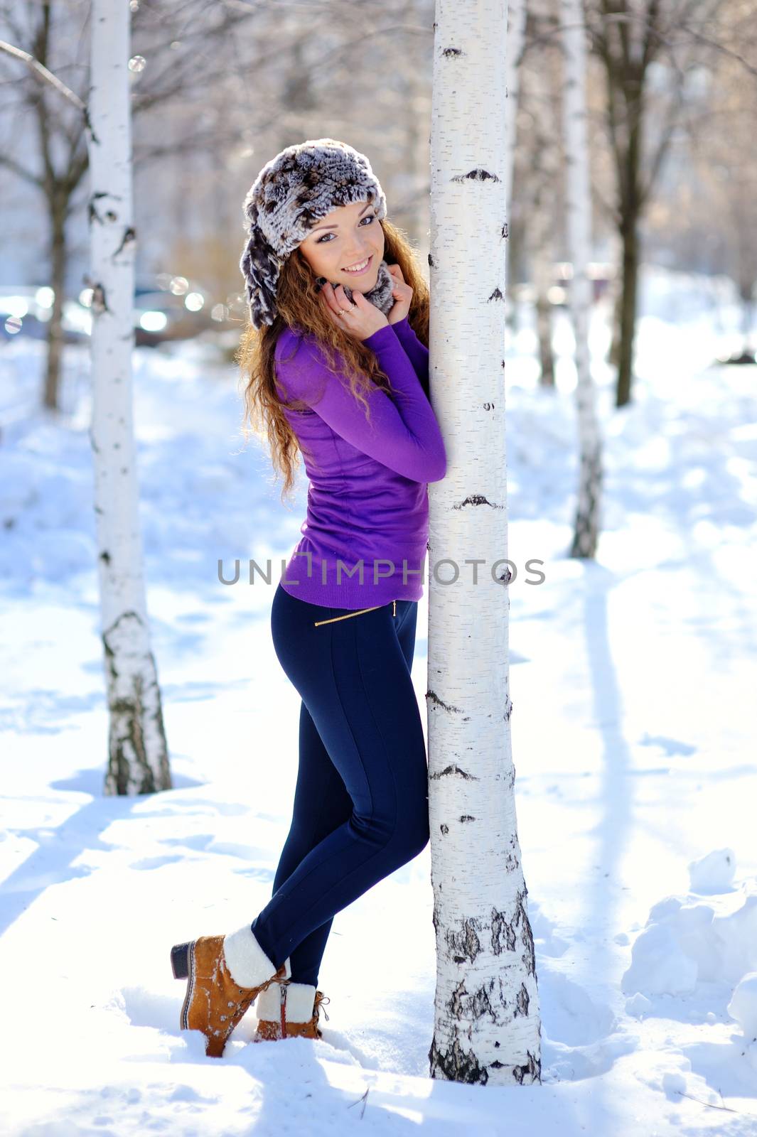 beautiful brunette standing near birch in winter