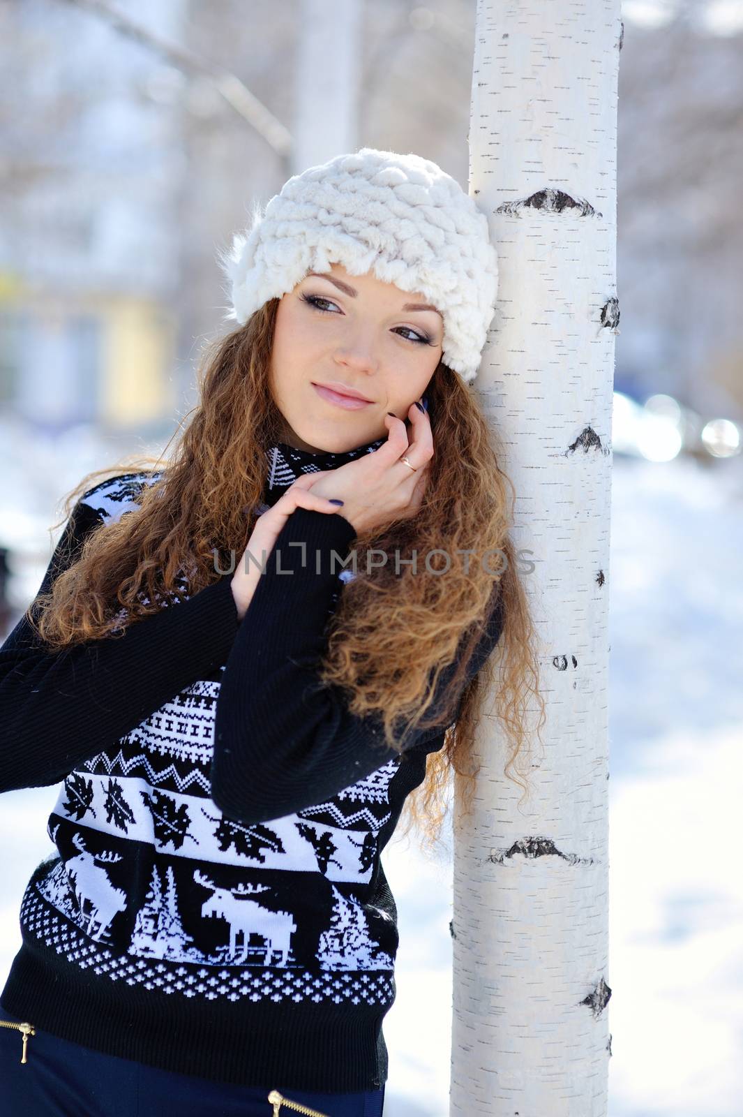 Young brunette girl in stripe sweater and white snow boots posing in the snow field. 