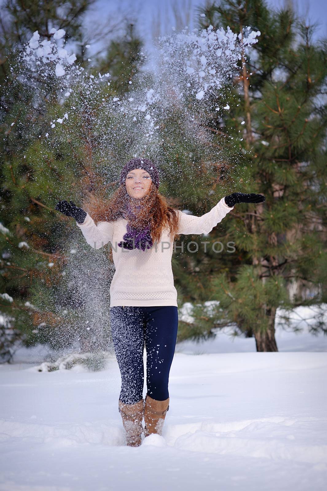 beautiful girl in winter snow throws hands