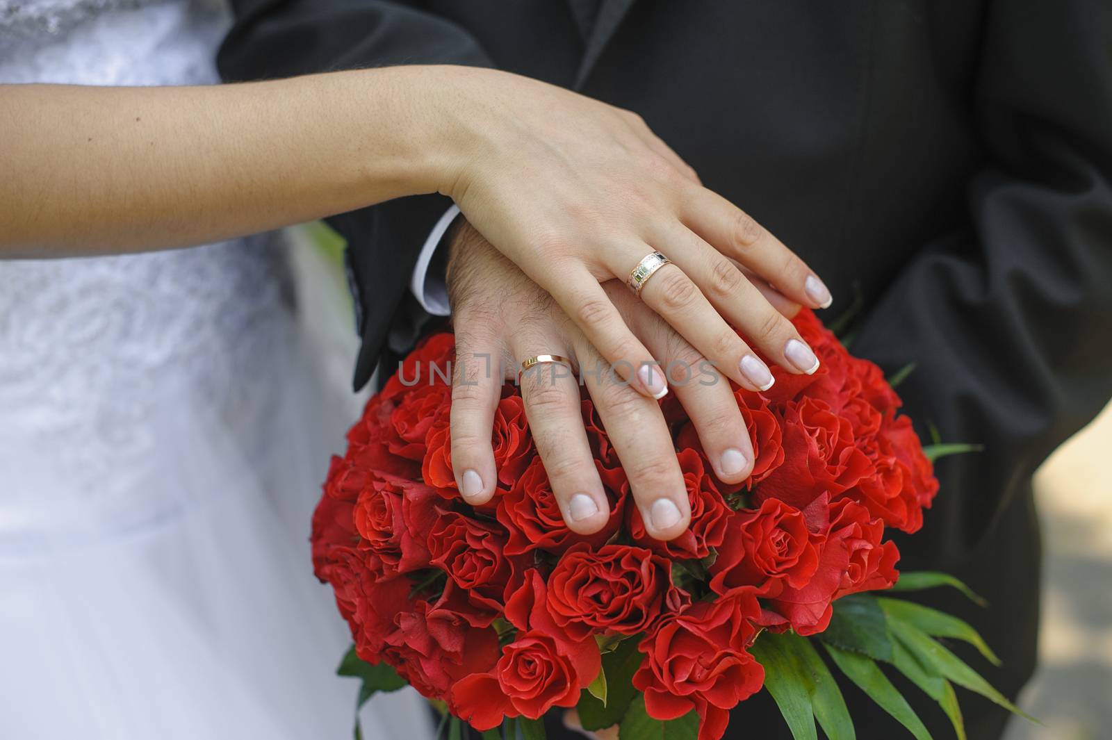 Hands and rings bride and groom on wedding bouquet