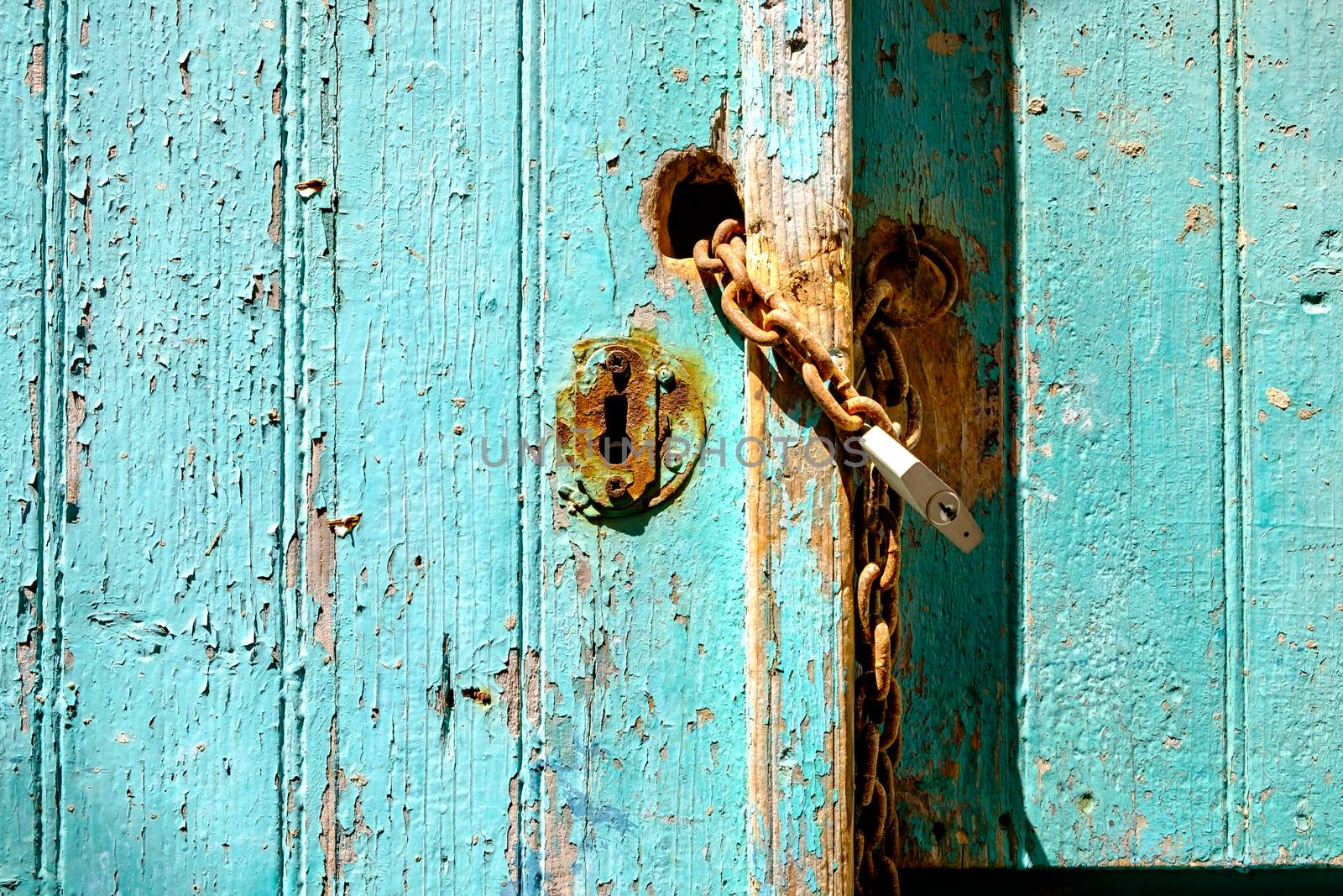 Old rusty padlock and chain on weathered textured door by martinm303