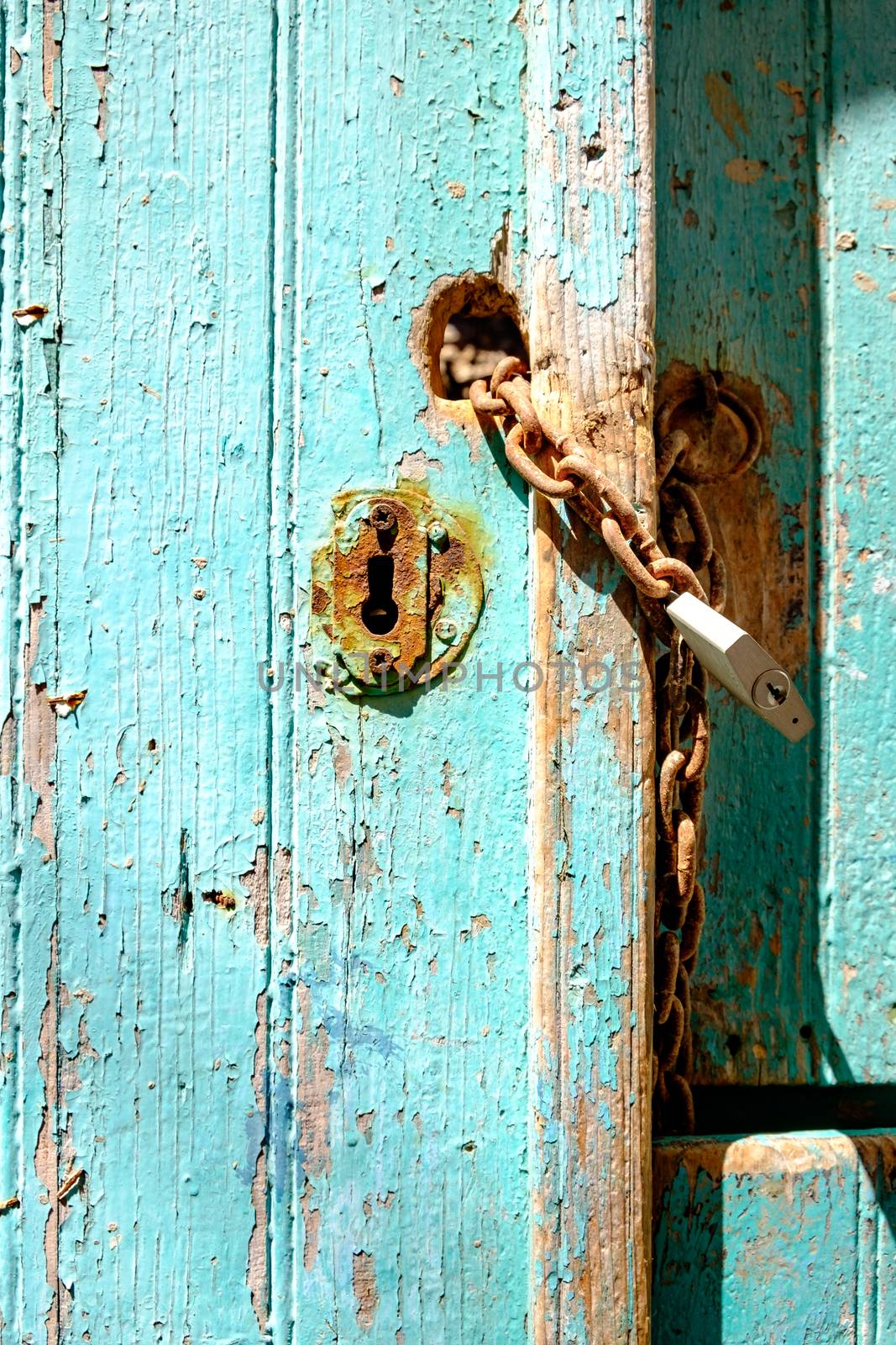 Old rusty padlock and chain on weathered textured door