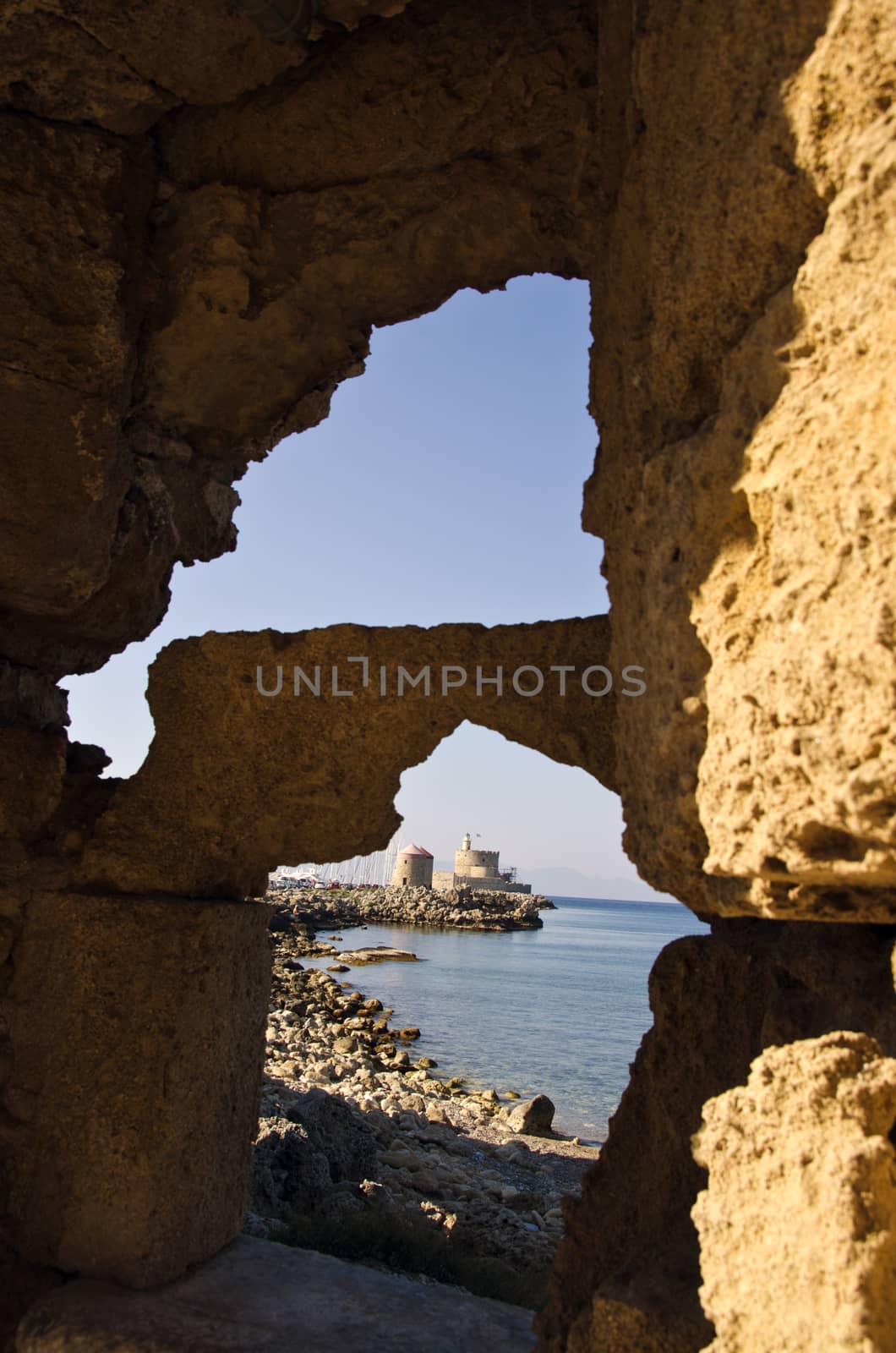 Fortress seen through the holes in cliffs in Rhodes island, Greece