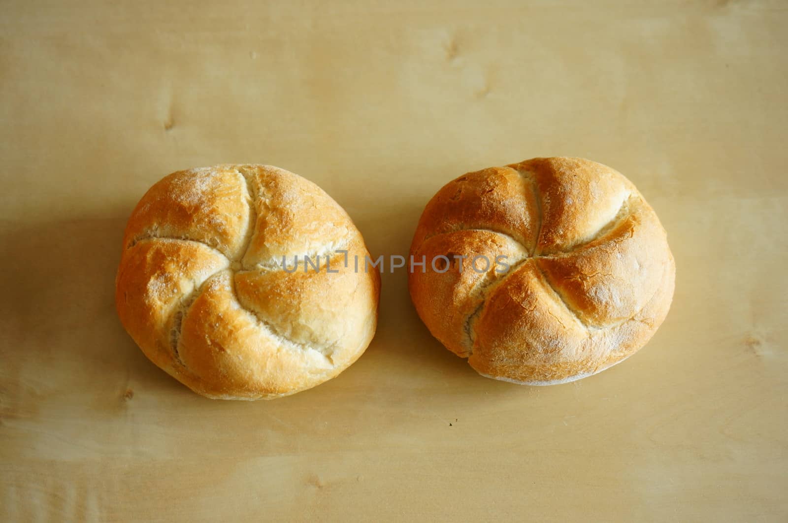 Two whole breads on wooden background