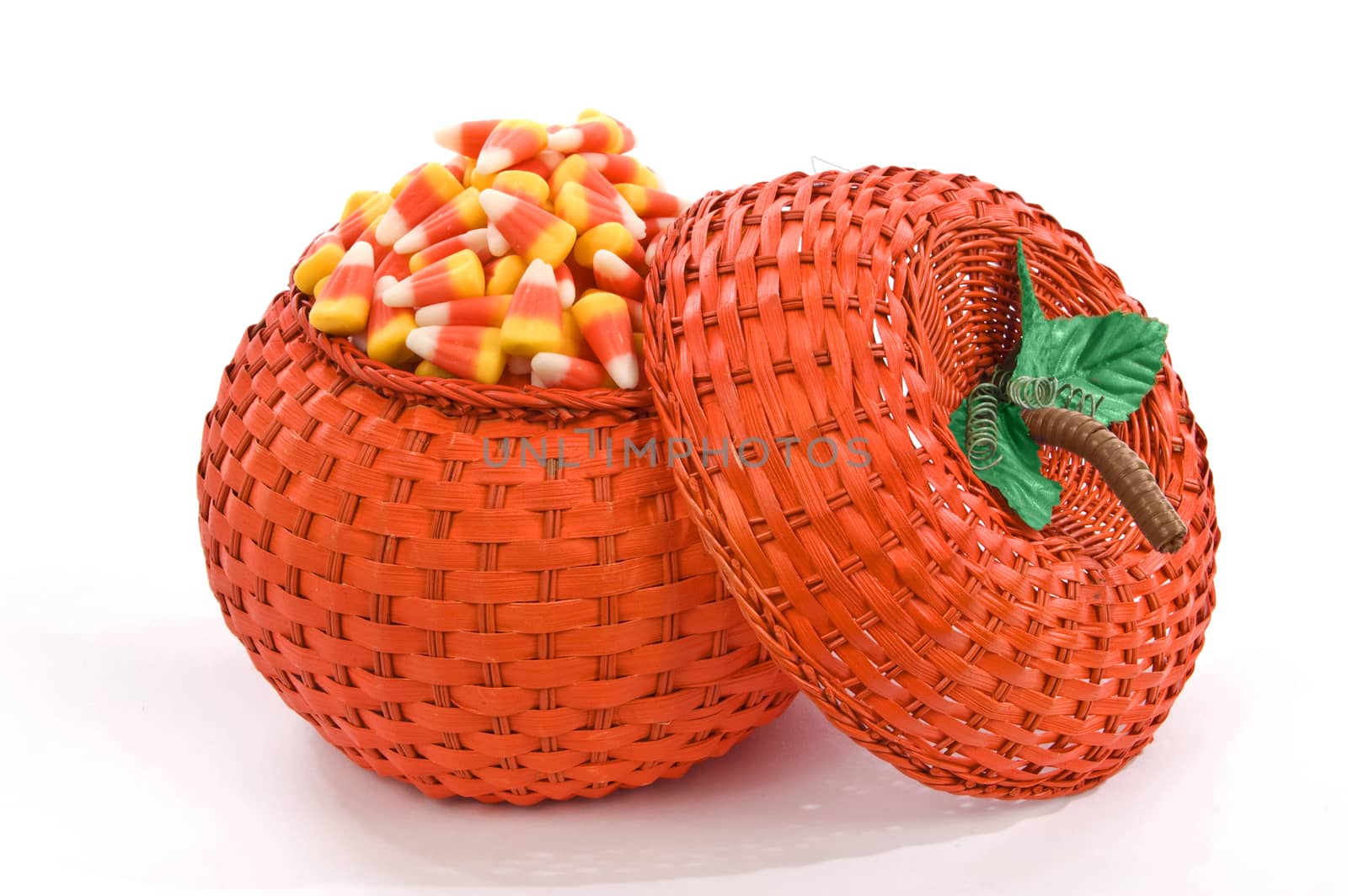 Wicker pumpkin basket full of sweet candy. On white background