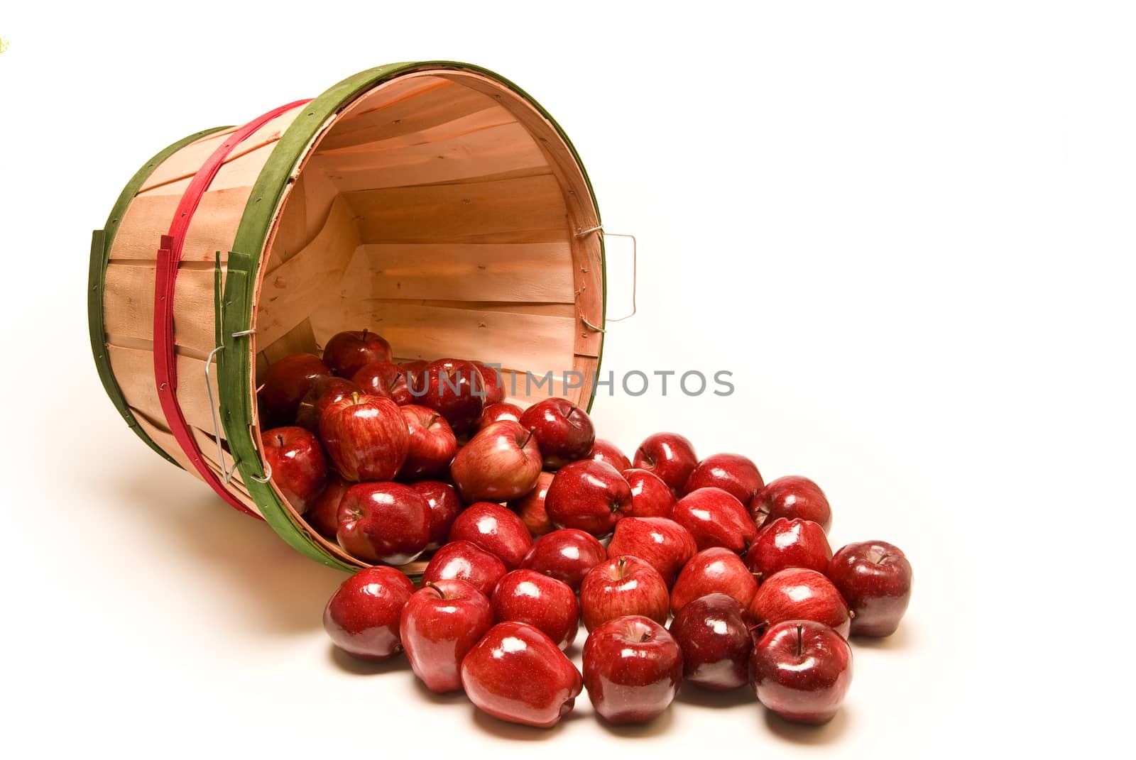 Horizontal shot of a large bushel basket of apples spilling out on a white background.