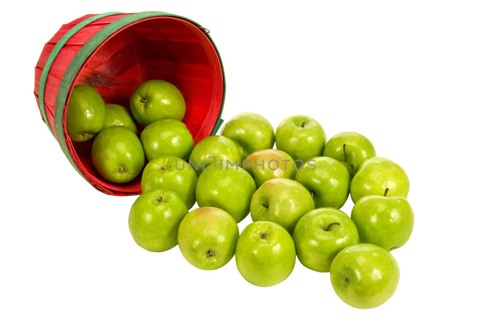 Horizontal shot of a little red basket of green apples spilling out on white background