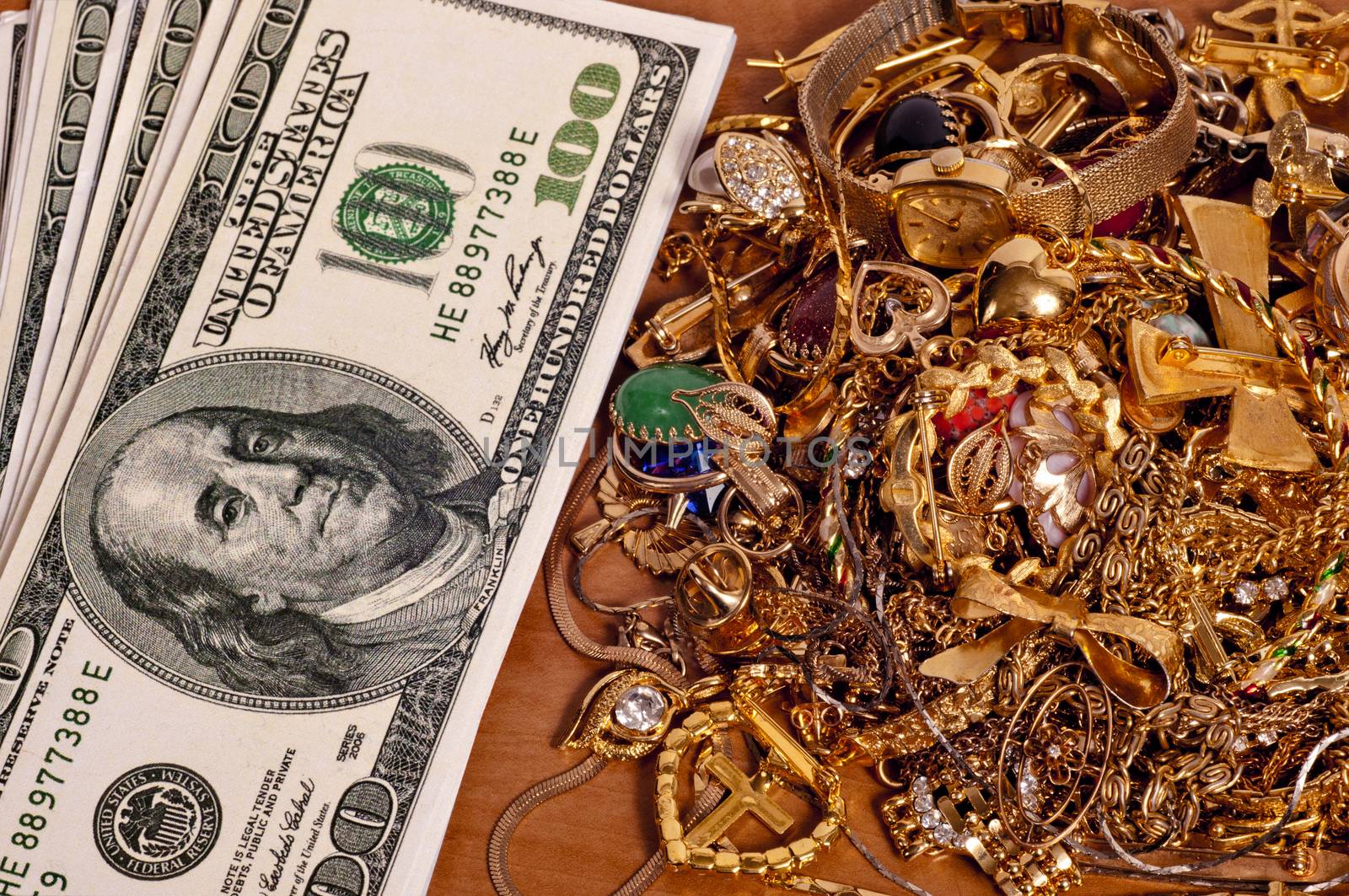 Horizontal shot of lots of cash next to a pile of jewelry.  Concept of selling your gold jewelry for big bucks.