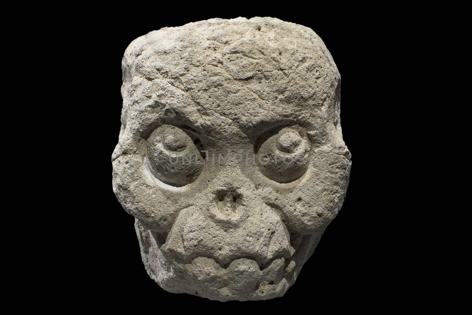 Closeup fleshless stone Mayan skull from Copan, Honduras isolated on black background