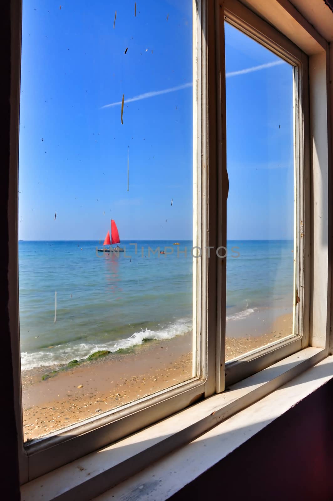 View from the window of an old thrown house on a boat with red sails, located on the Black Sea coast