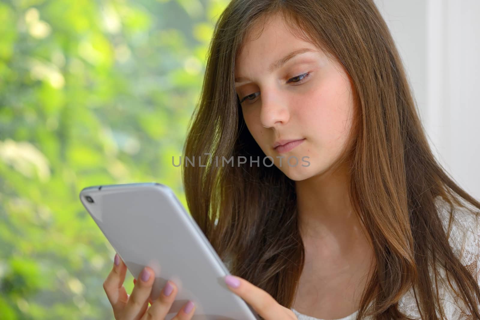 Serious young girl reading information on a tablet computer