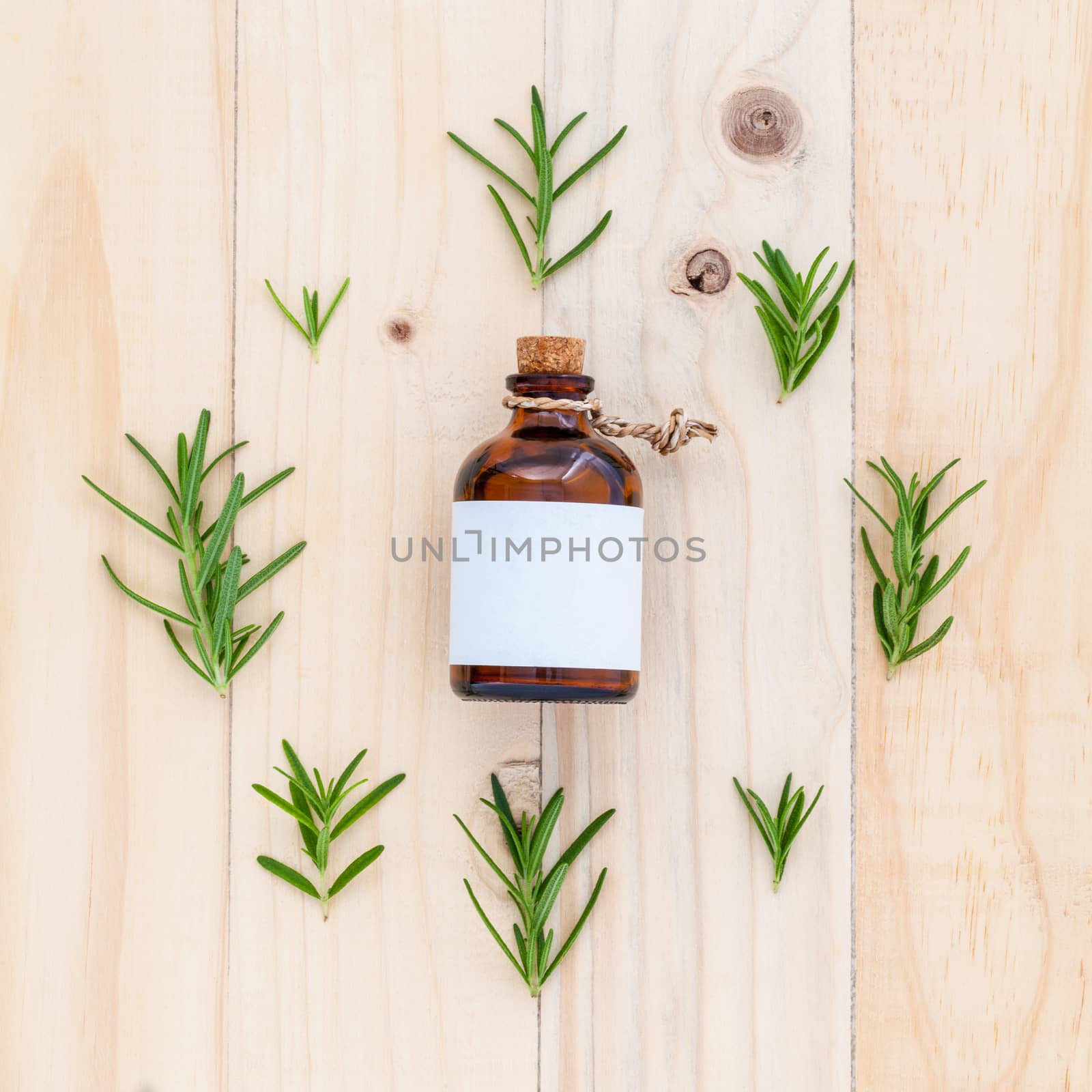 Natural Spa Ingredients rosemary essential oil for aromatherapy with circle of rosemary  leaf on wooden background.