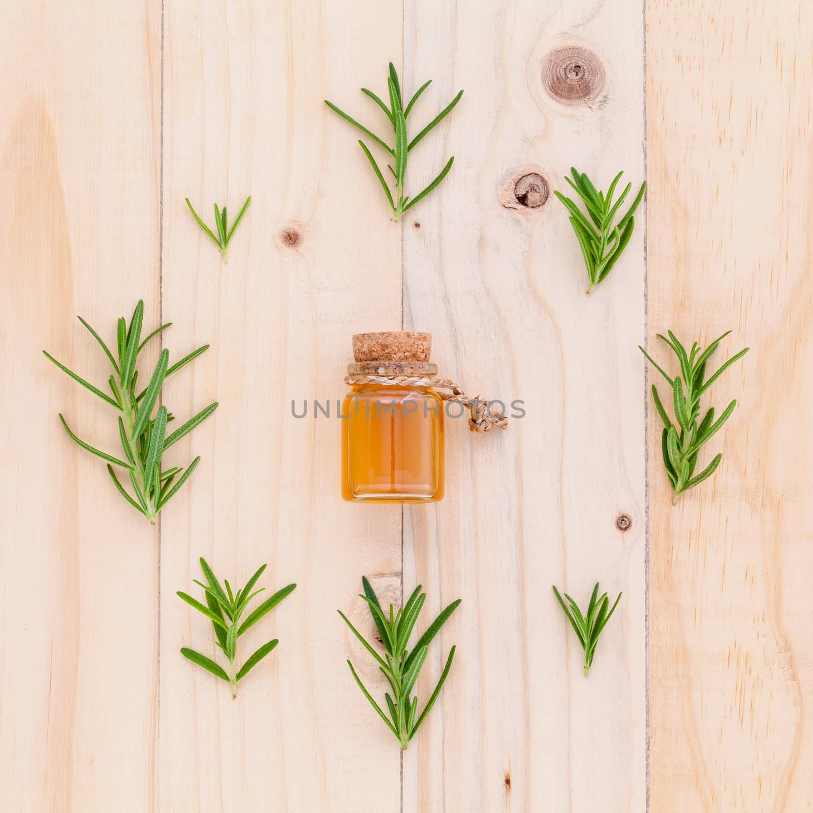 Natural Spa Ingredients rosemary essential oil for aromatherapy with circle of rosemary  leaf on wooden background.