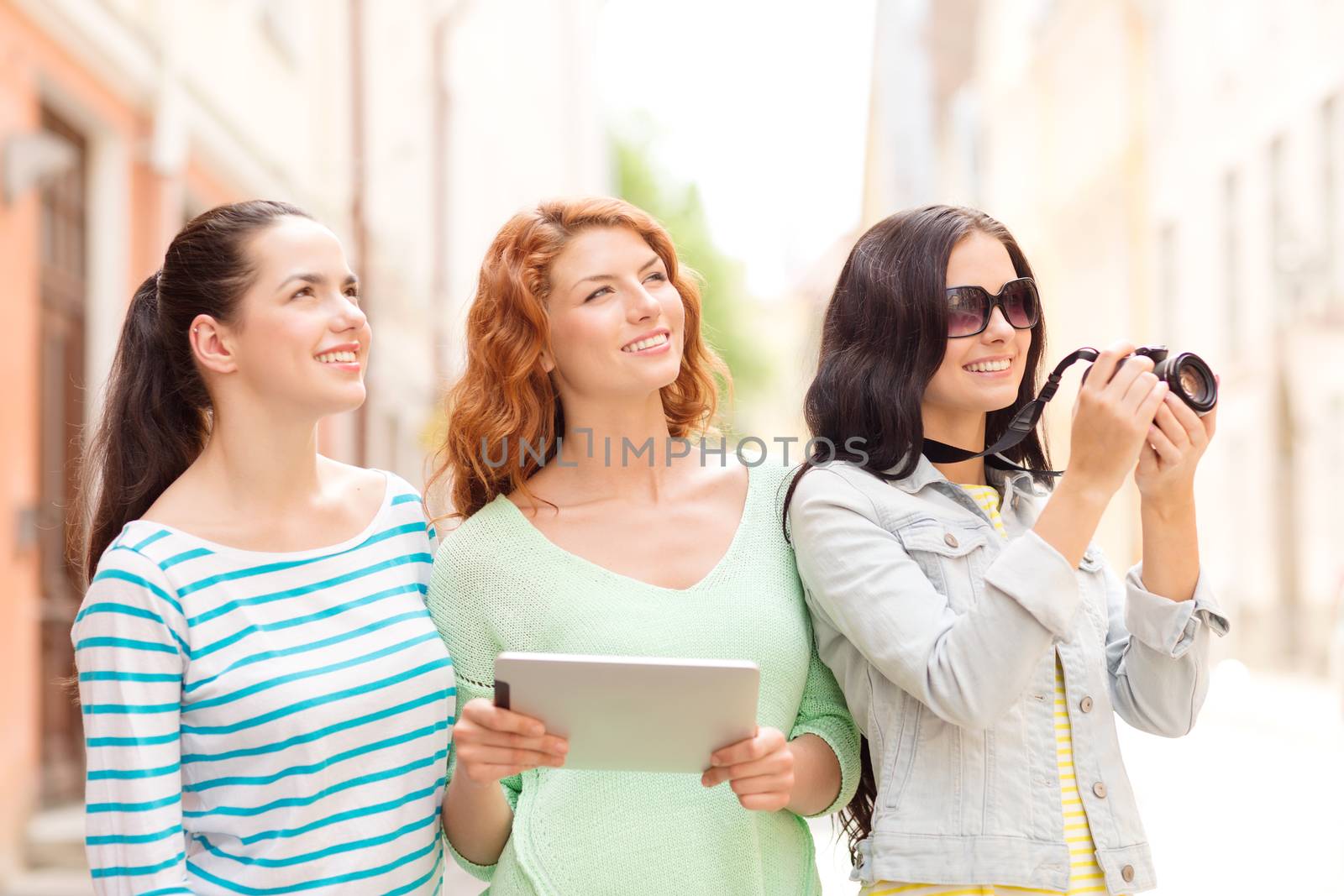 smiling teenage girls with tablet pc and camera by dolgachov