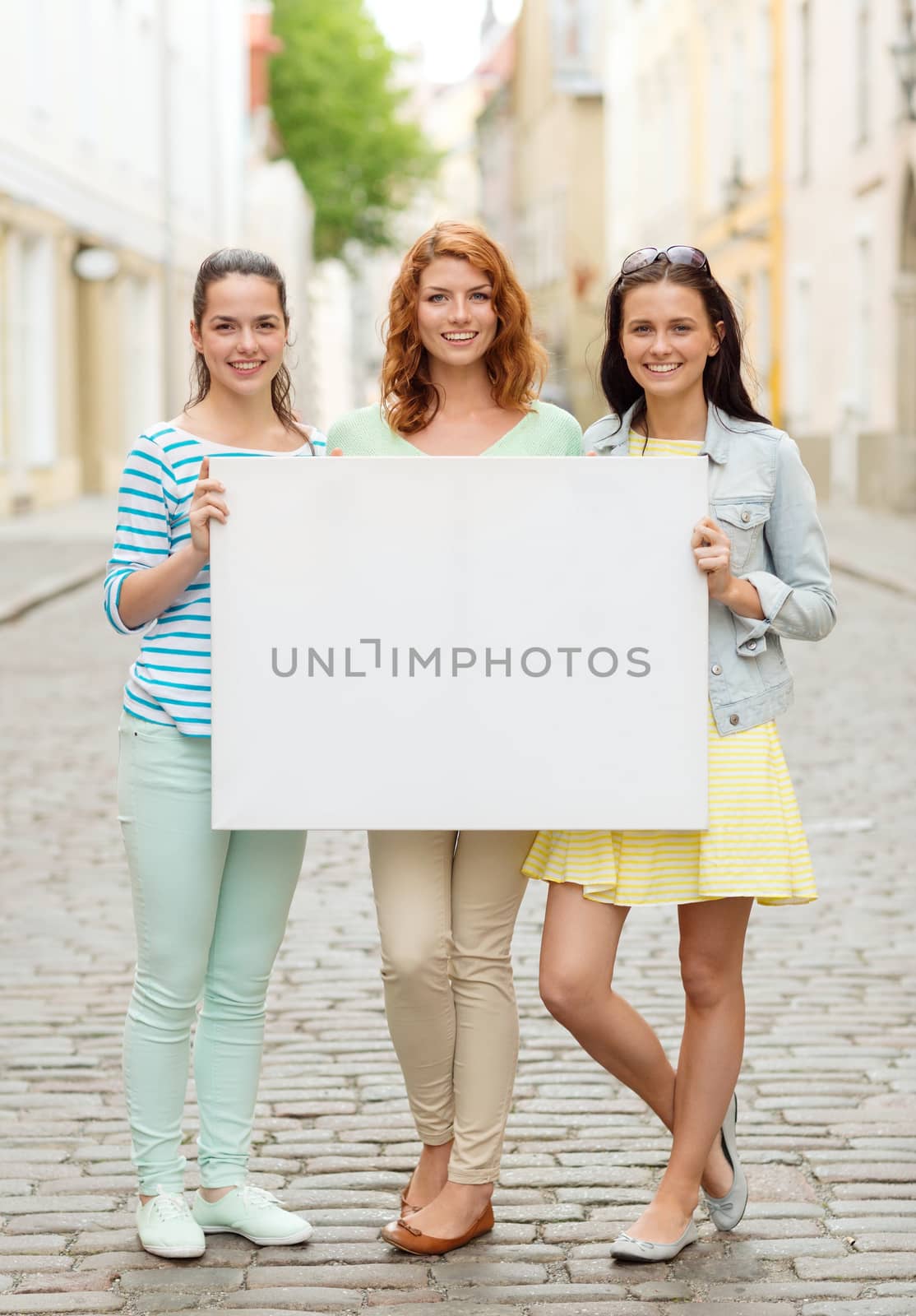 smiling teenage girls with blank billboard by dolgachov