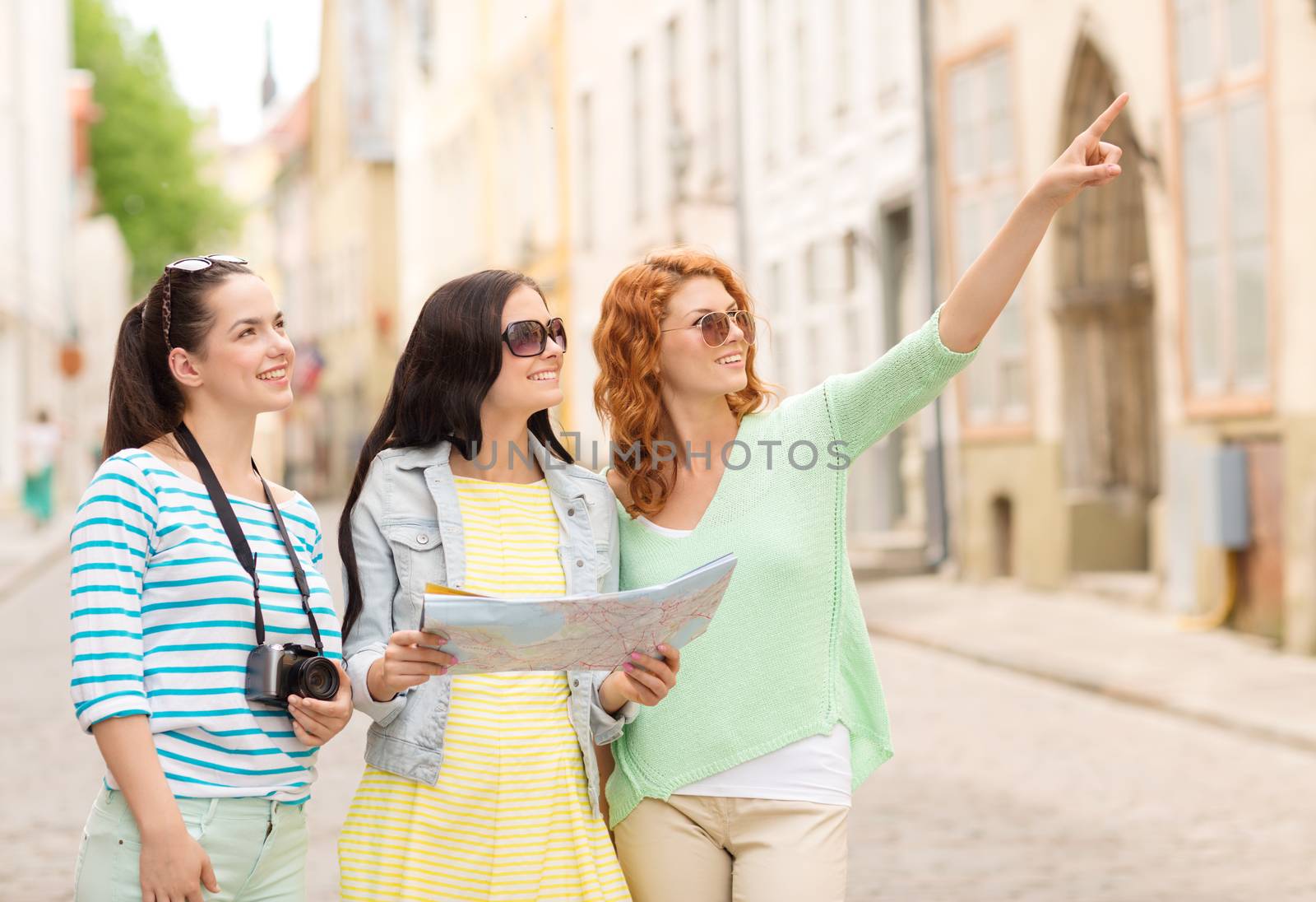 smiling teenage girls with map and camera by dolgachov