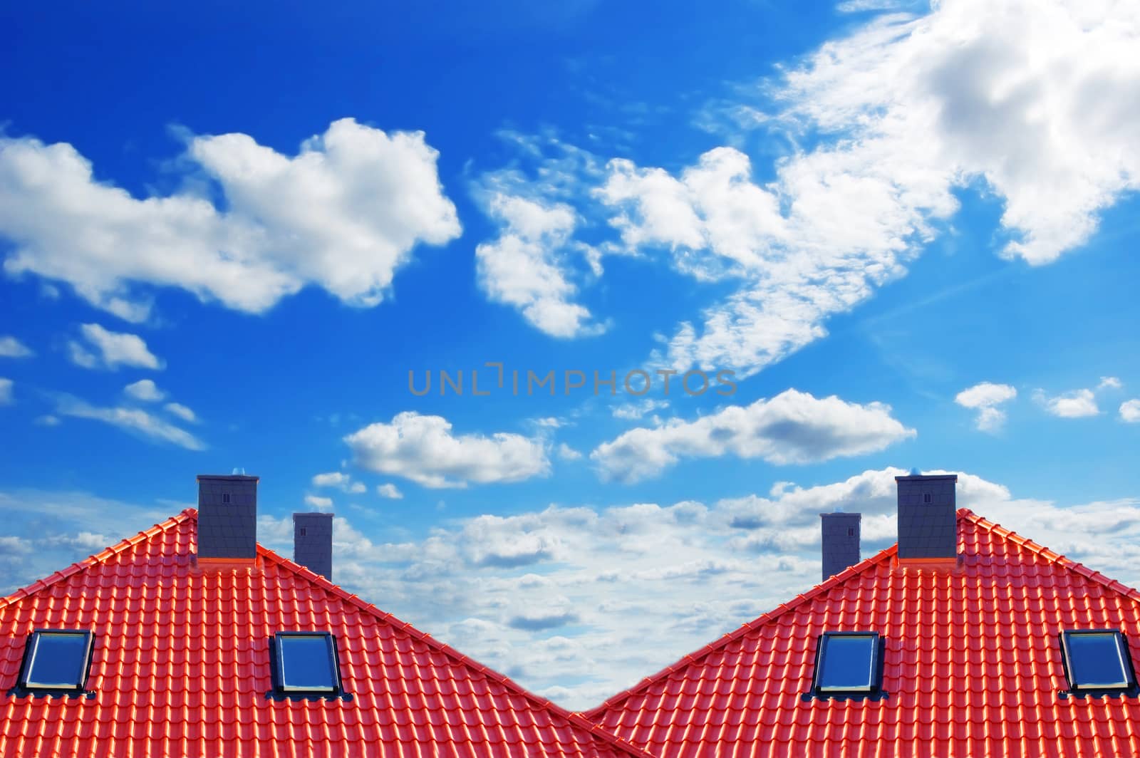 Red roof of new detached houses against blue sky.