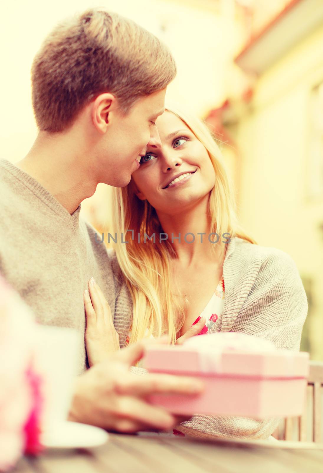 summer holidays, love, travel, relationship and dating concept - romantic happy couple with gift in the cafe