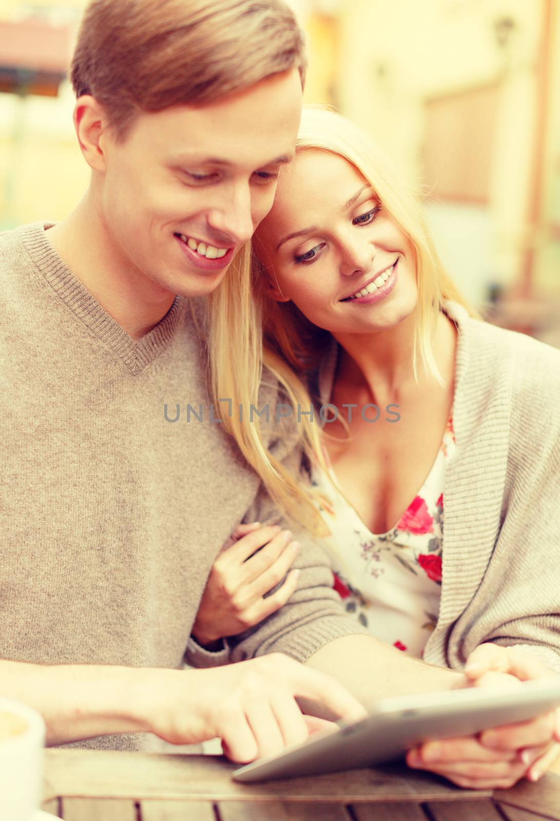 smiling couple with tablet pc computer in cafe by dolgachov