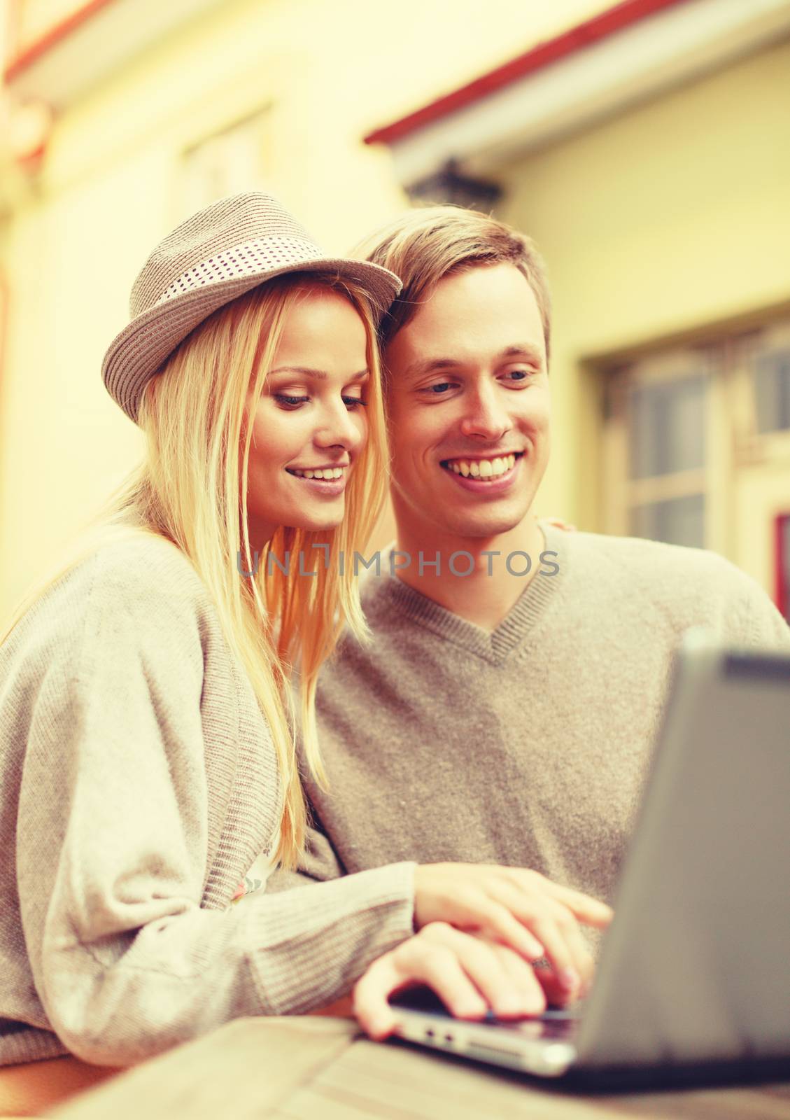 summer holidays, city, dating and technology concept - smiling couple with laptop computer in cafe