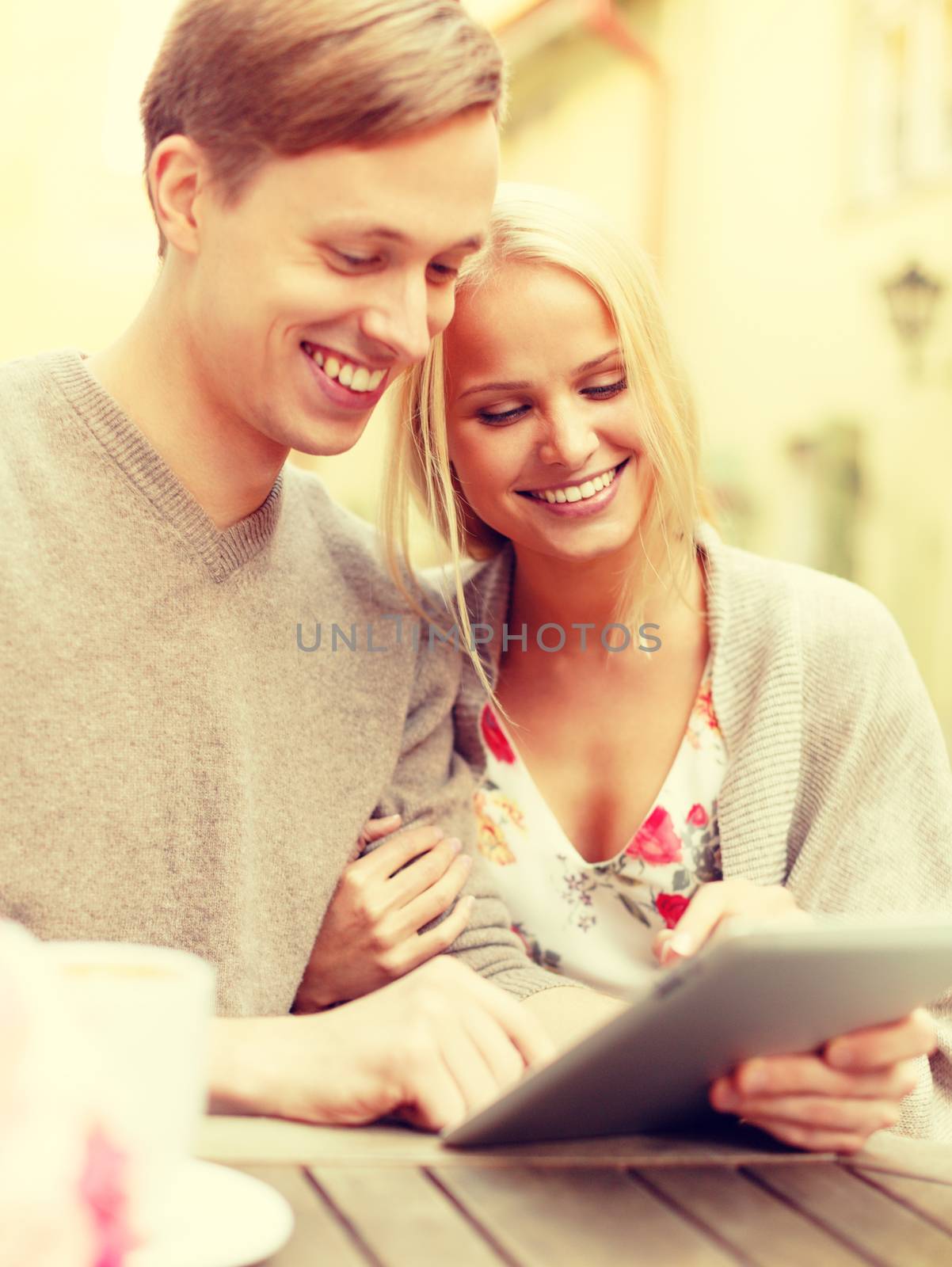 smiling couple with tablet pc computer in cafe by dolgachov