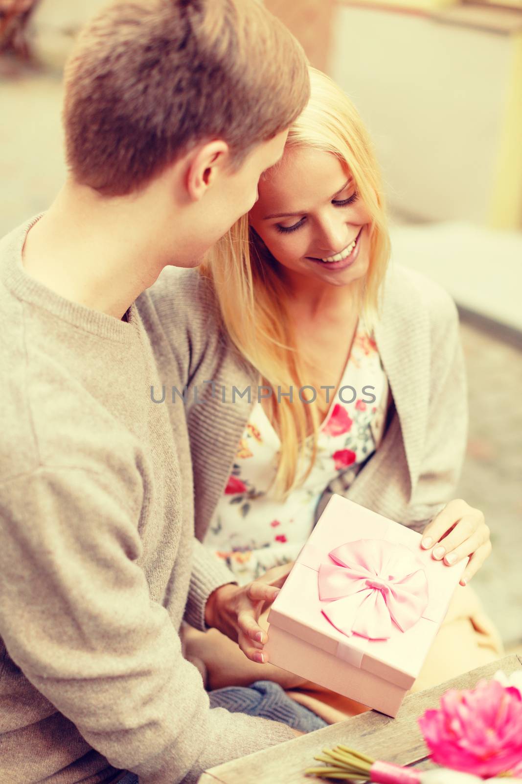 romantic happy couple with gift in the cafe by dolgachov