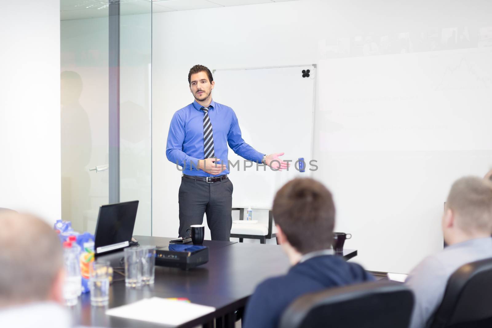 Business man making a presentation at office. Business executive delivering a presentation to his colleagues during meeting or in-house business training, explaining business plans to his employees.