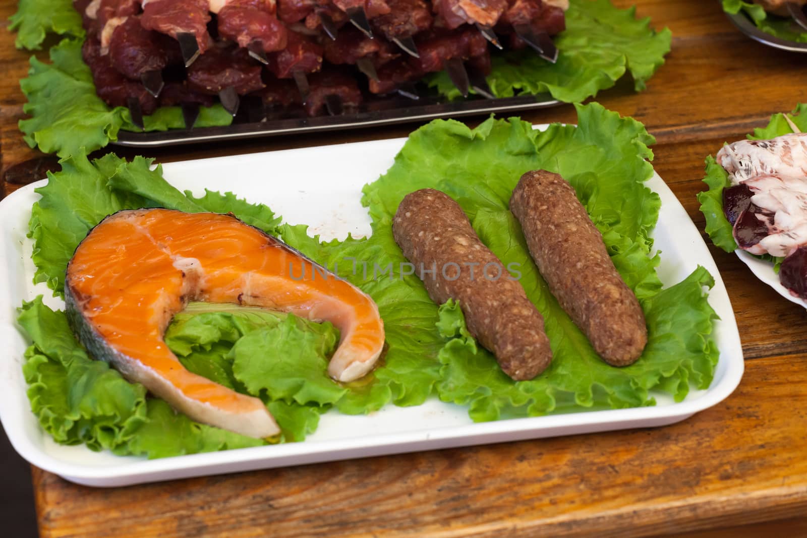 stake of a salmon on a white plate with greens on a wooden table