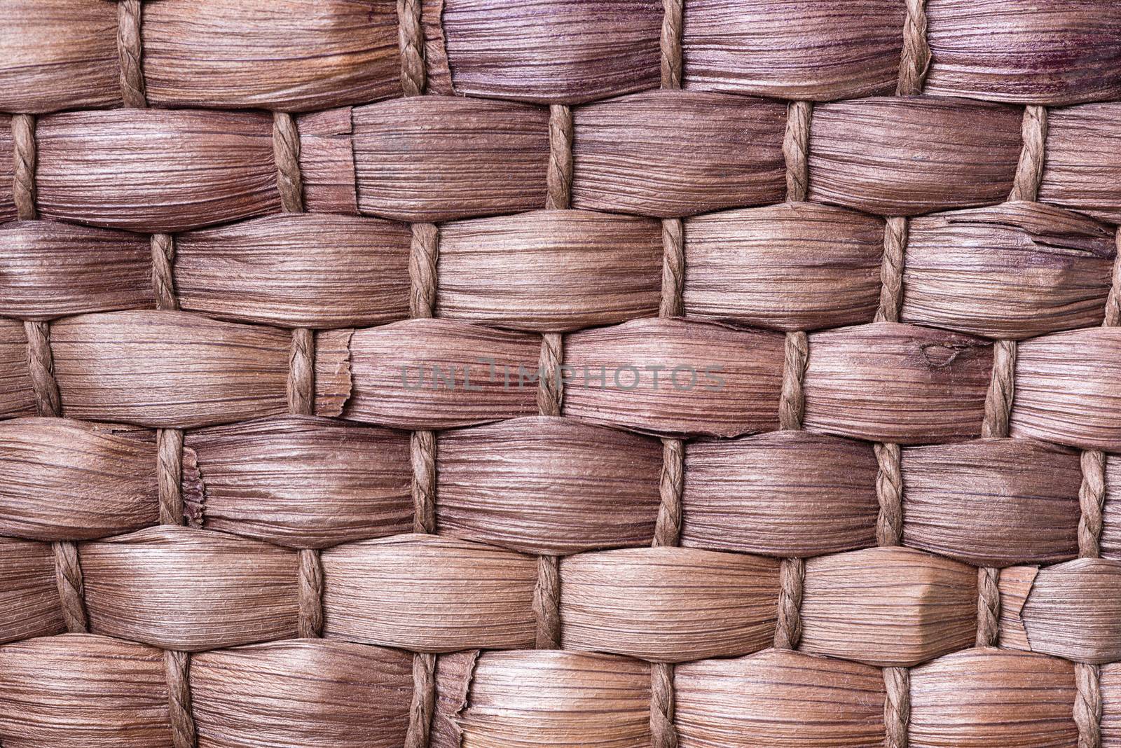 A macro shot of the woven fibers of a brown wicker basket.