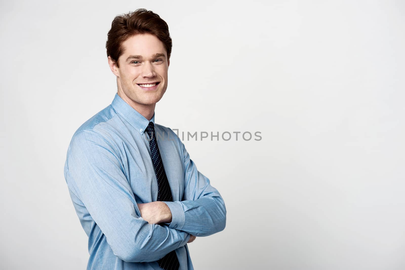 Smiling businessman with crossed arms by stockyimages