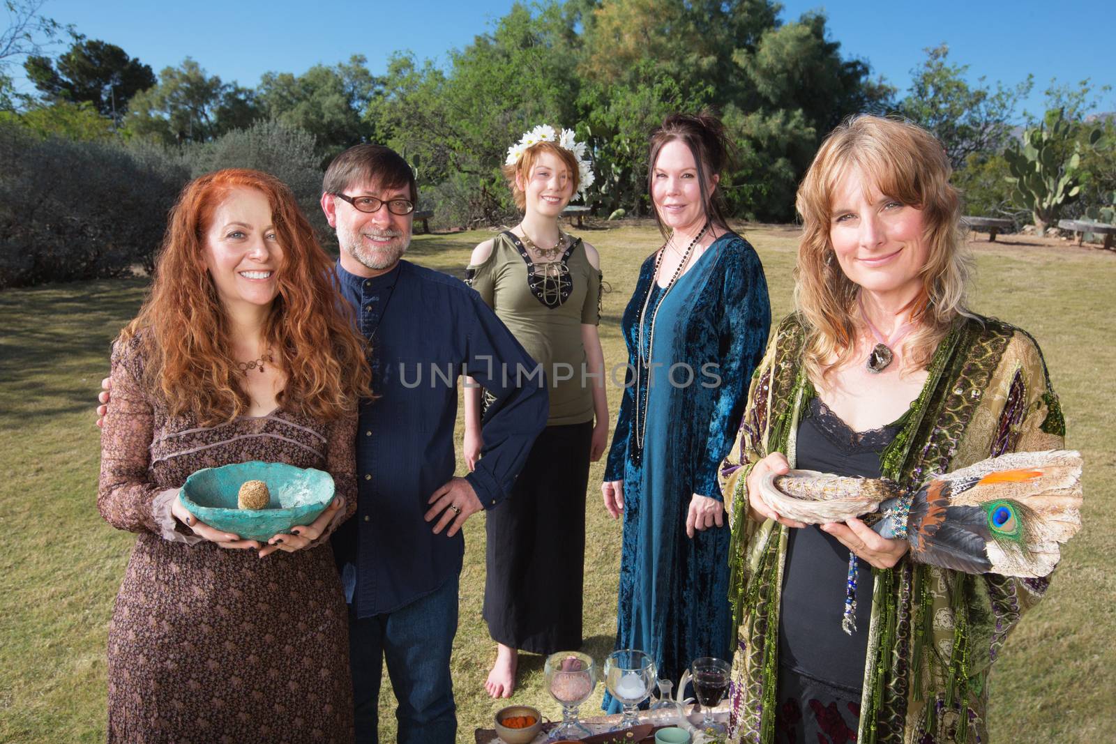 Five smiling Wicca practitioners standing outdoors with smudge stick