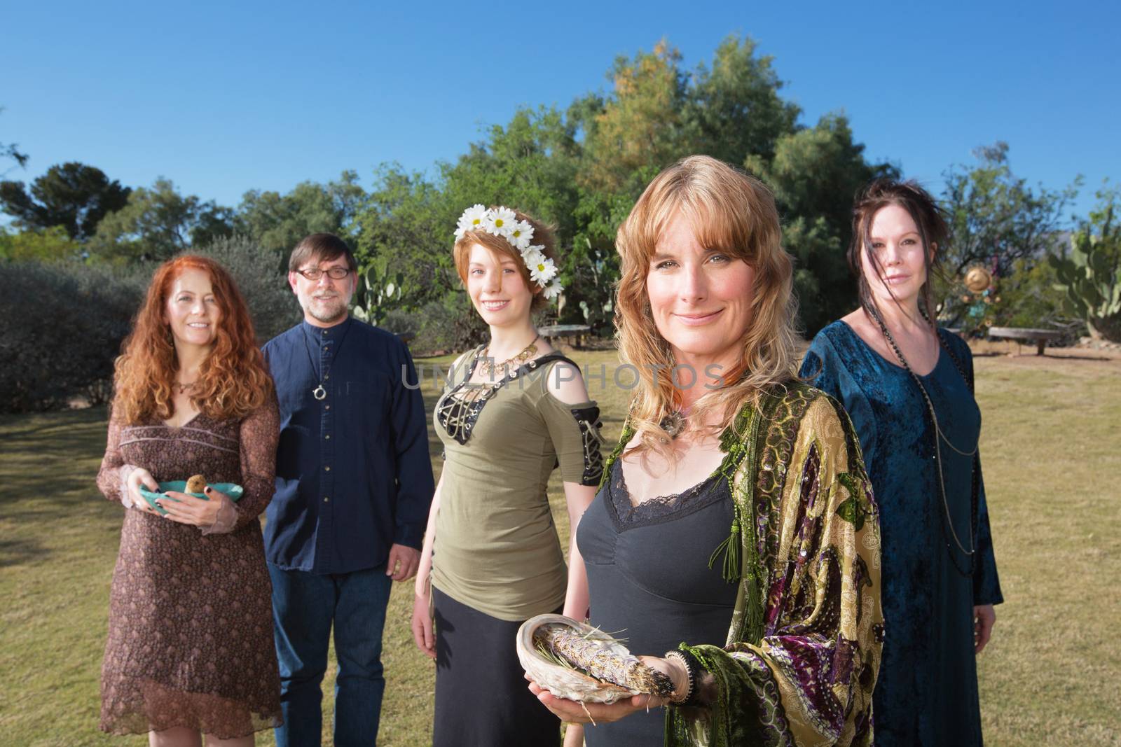 Group of Caucasian polytheists with smudge sticks standing outdoors