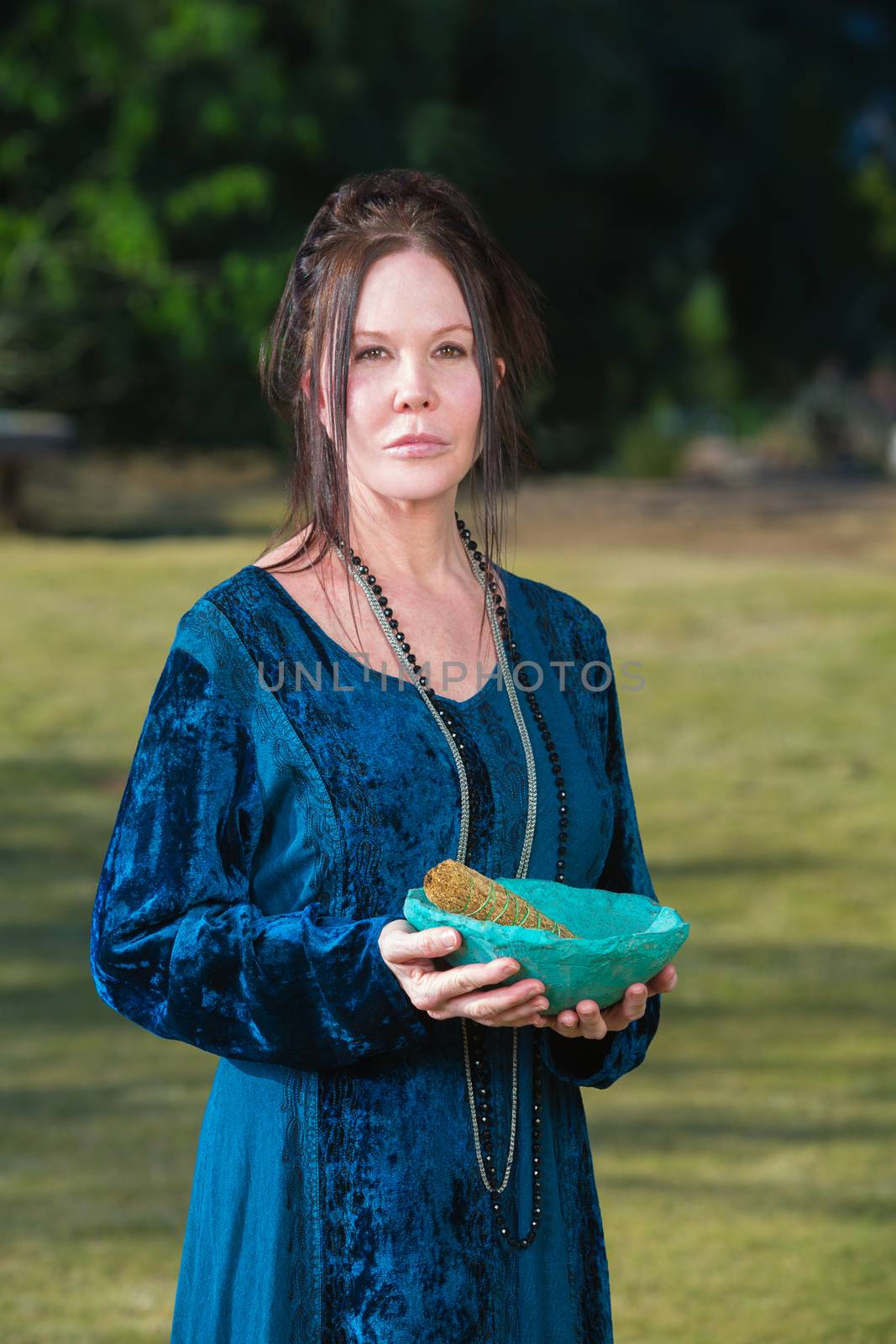 Serious Wicca priestess with blue bowl sage incense