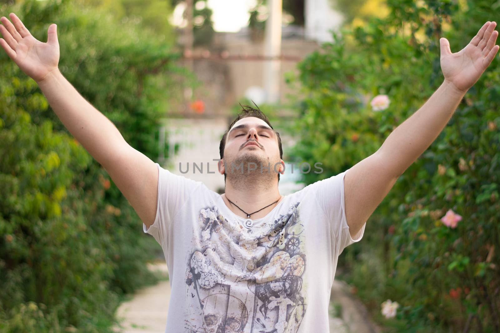 Young man with his hands up in the air, facing the sky.