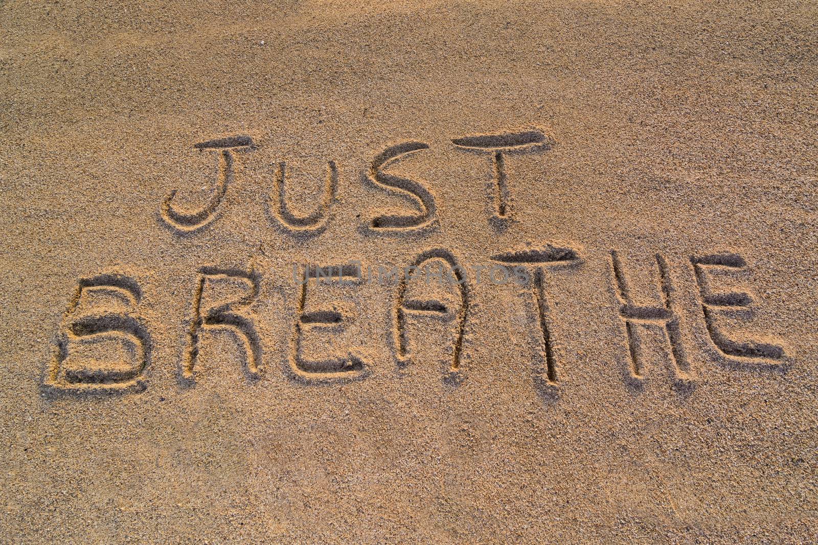 In the picture the words on the sand "Just breathe".