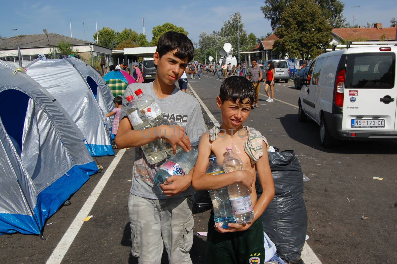 SERBIA, Horgo�: Two young migrant boys hold water near the Serbia-Hungary border in Horgo�, Serbia on September 17, 2015. Recently the migrants have clashed with police forcing the police to use tear gas and water cannons to hold the refugees at bay. The migrants demanded that the razor-wire fence be opened, which would allow them to continue their journey though Europe. 