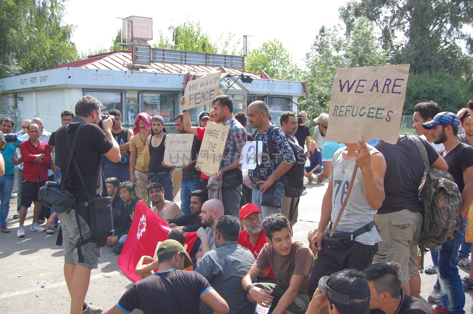 SERBIA, Horgo�: Migrants gather holding signs and flags in Horgo�, Serbia on September 17, 2015. Recently the migrants have clashed with police forcing the police to use tear gas and water cannons to hold the refugees at bay. The migrants demanded that the razor-wire fence be opened, which would allow them to continue their journey though Europe. 