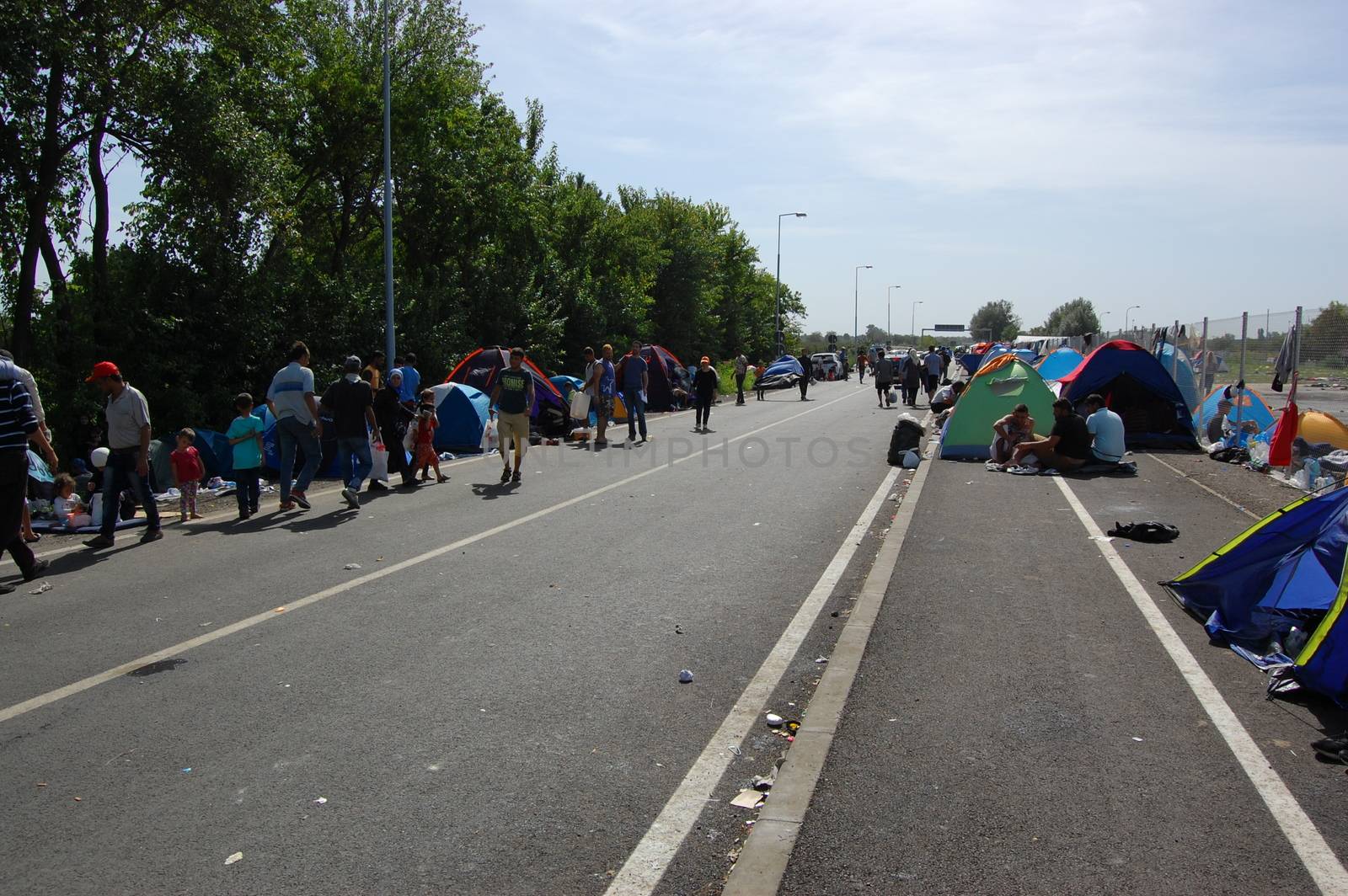 SERBIA, Horgo�: Migrants walk along a road and sit in tents at the Serbia-Hungary border in Horgo�, Serbia on September 17, 2015. Recently the migrants have clashed with police forcing the police to use tear gas and water cannons to hold the refugees at bay. The migrants demanded that the razor-wire fence be opened, which would allow them to continue their journey though Europe. 