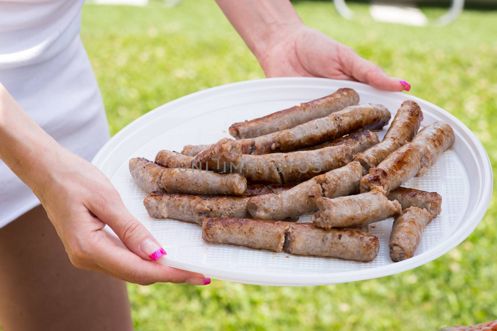Woman serving sausage on grill party.