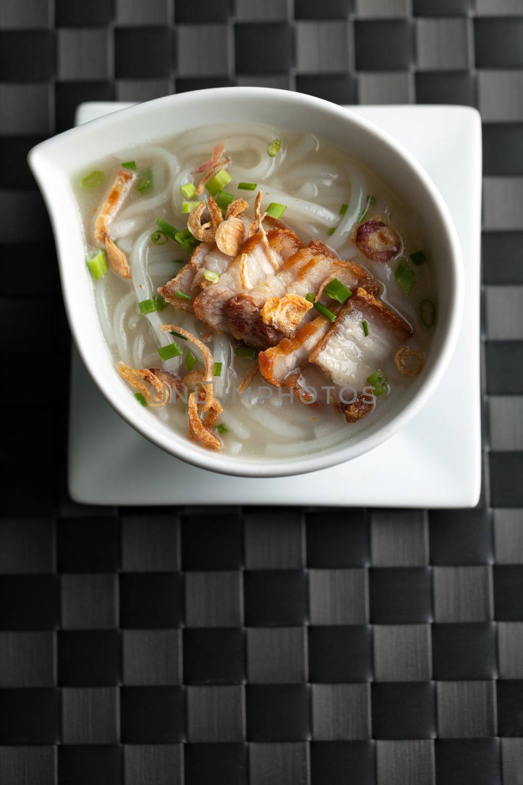 Close up top down view of Thai style crispy pork rice noodle soup in a bowl with copy space.